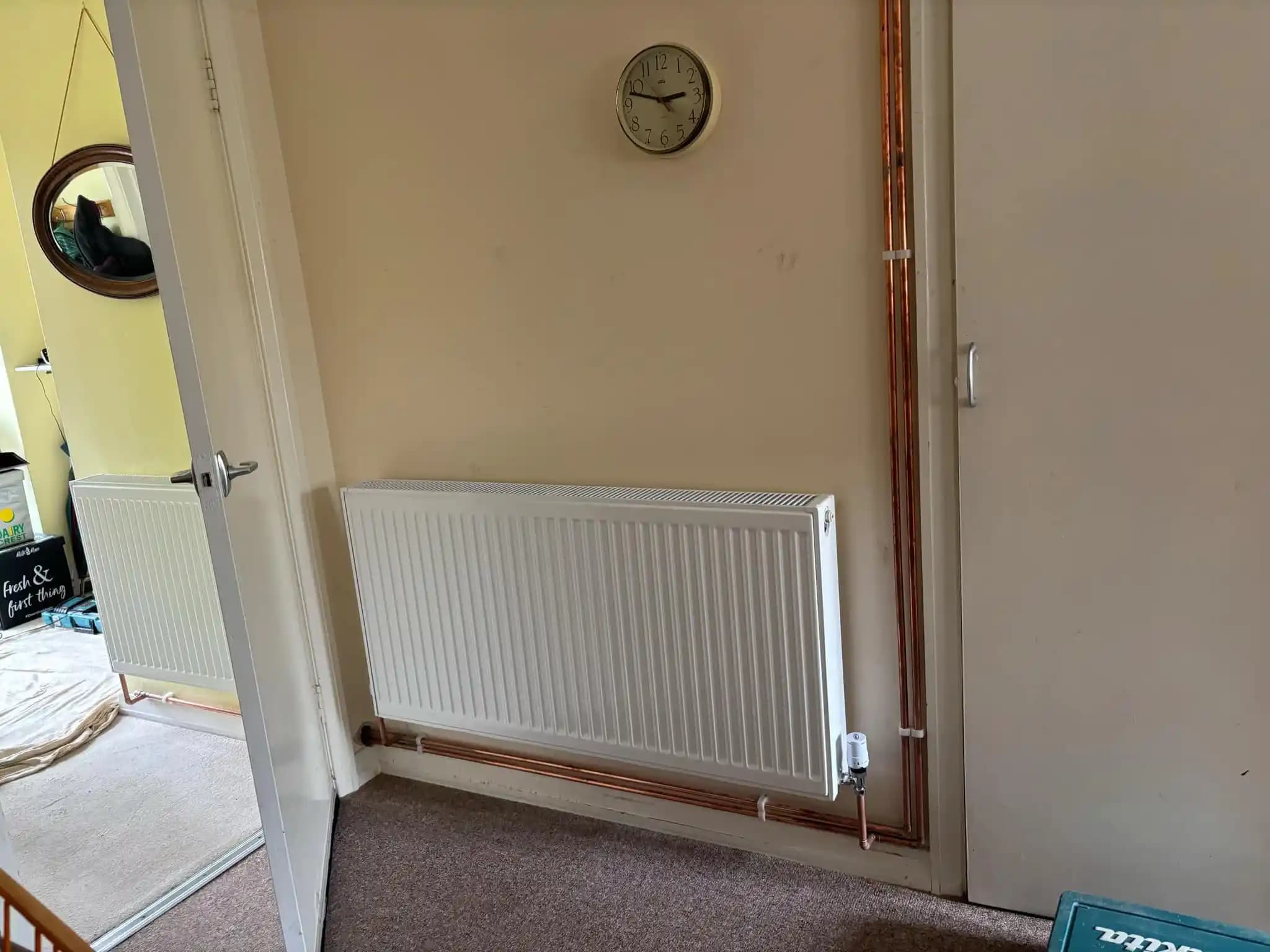 White radiator installed with exposed copper pipework.