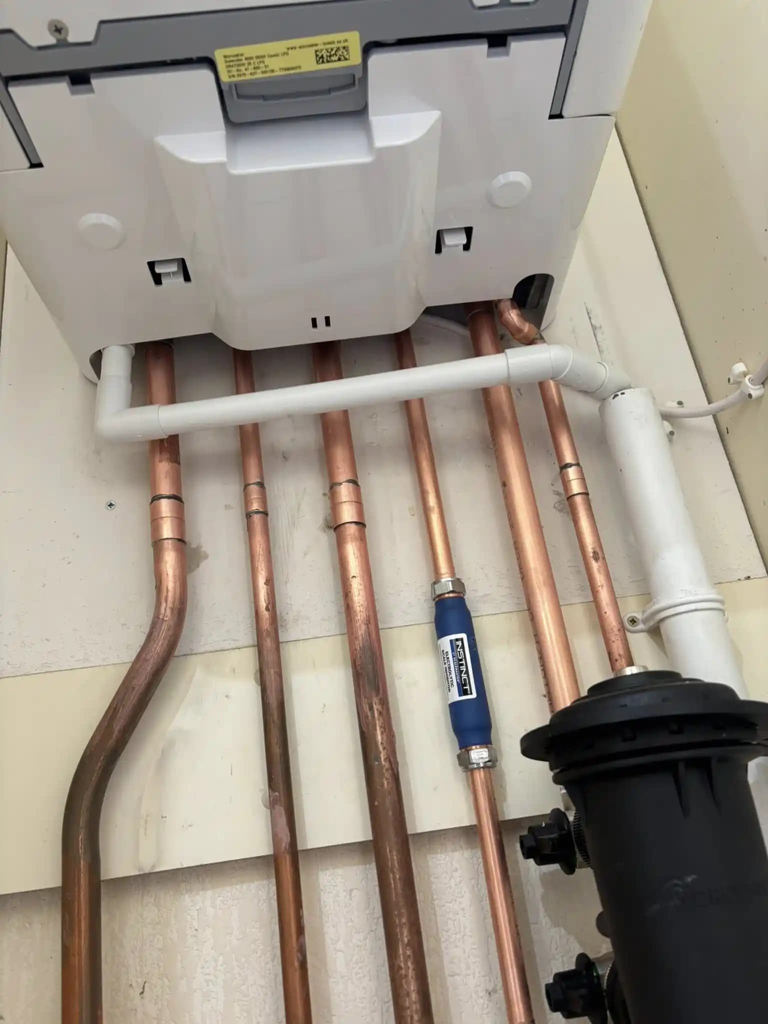 Close-up of boiler pipework with copper pipes, condensate pipe and magnetic filter.
