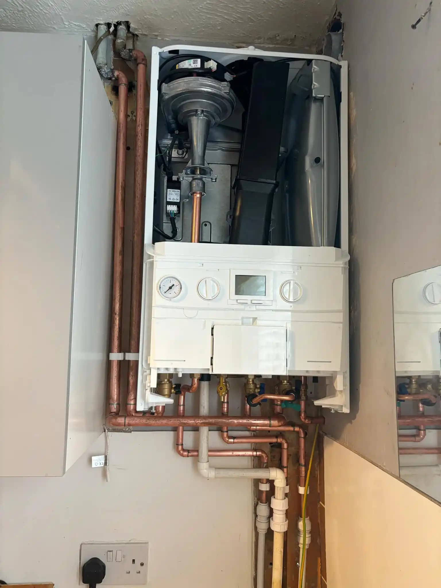 Open combi boiler showing internal components and copper pipework.