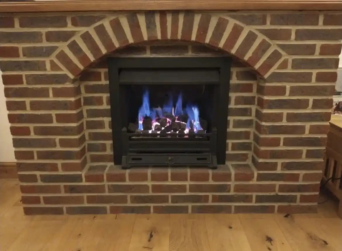 Serviced gas fire burning in a brick fireplace.