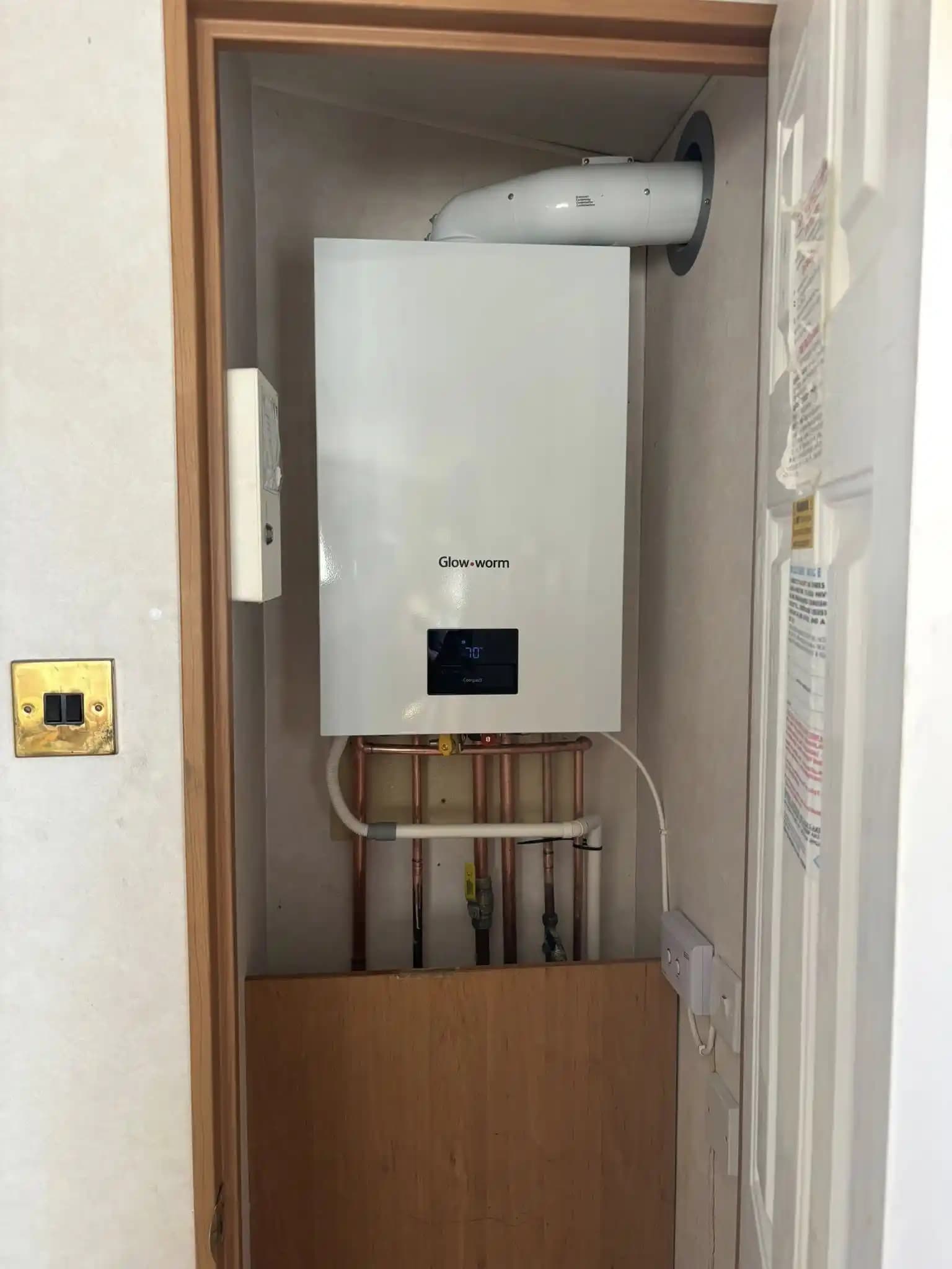 Glow-worm boiler fitted neatly inside a cupboard with copper pipework.