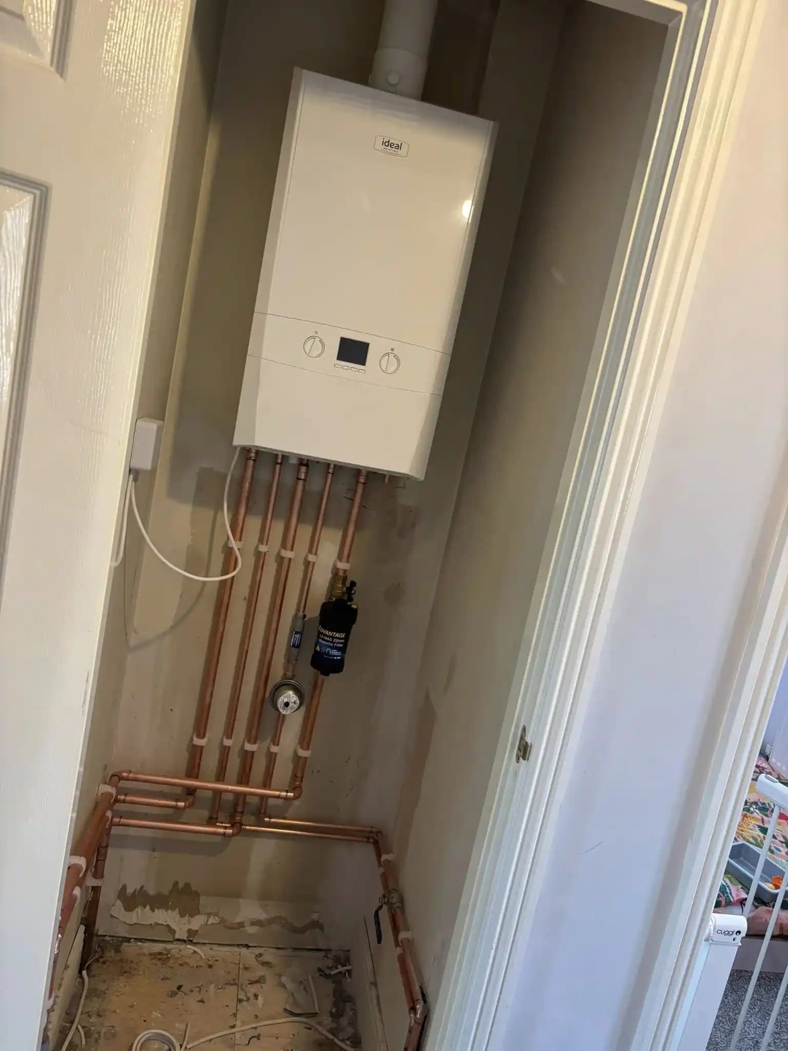 Ideal combi boiler installed in a cupboard with copper pipework and filter.