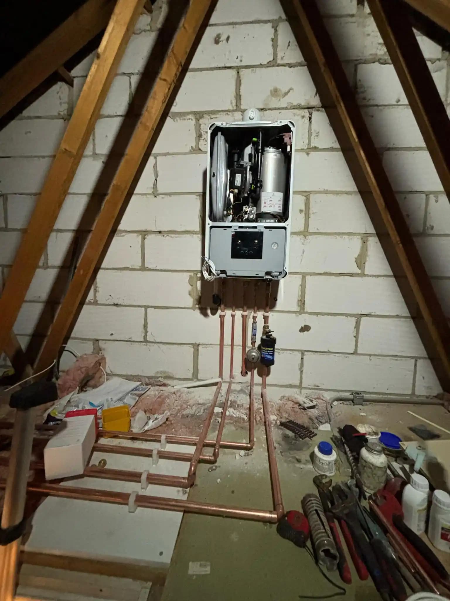 Boiler installation in a loft space with copper pipework.