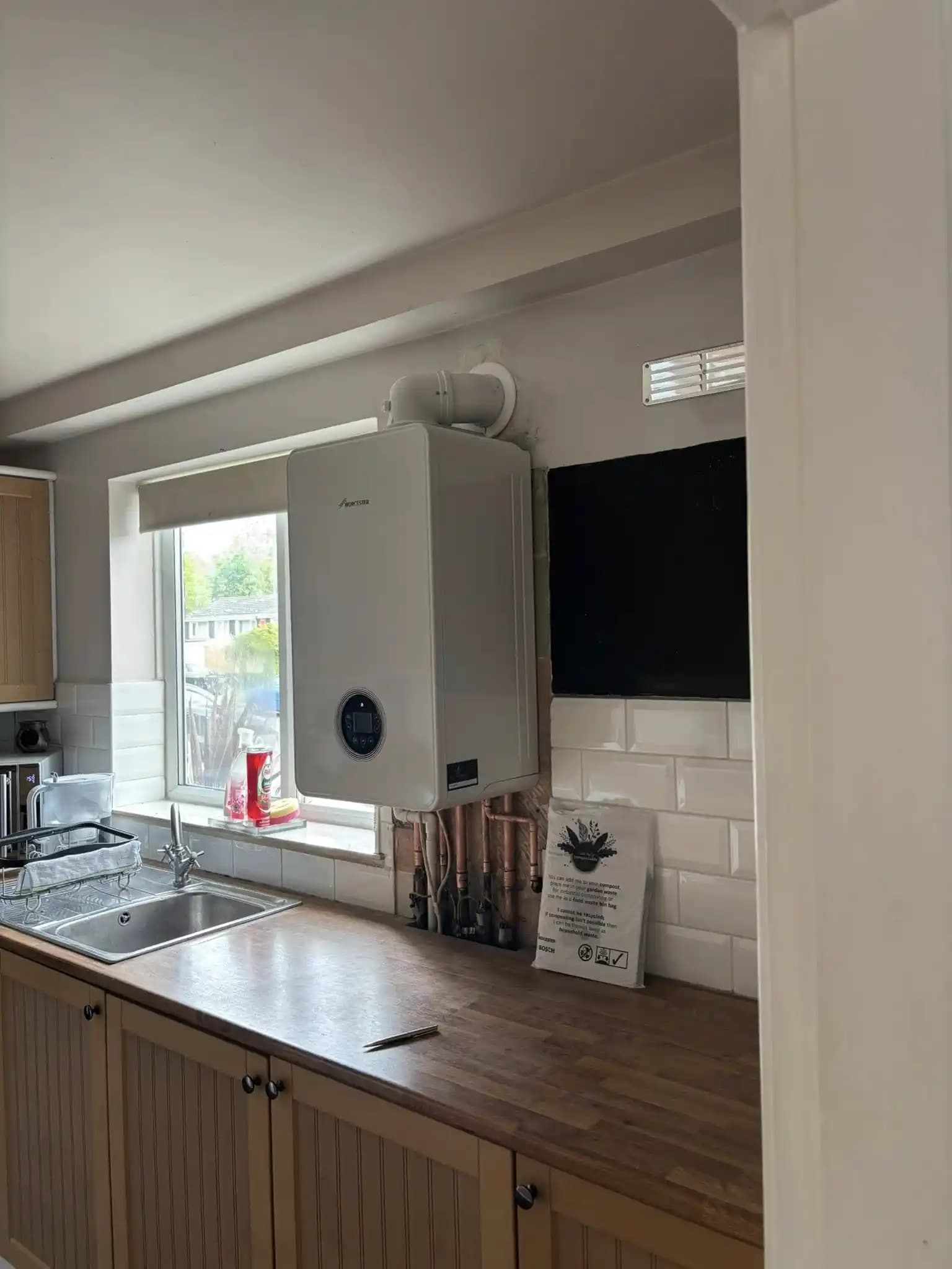 Side view of a Worcester boiler installation in a kitchen with exposed pipework.